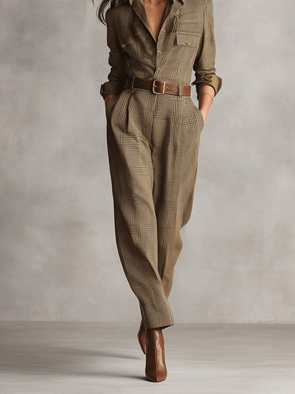 Brown - A woman wearing a tailored, long-sleeve glen plaid jumpsuit in olive and brown tones, featuring a point collar, button-front closure, utility pockets, and pleated tapered trousers cinched with a brown leather belt.
