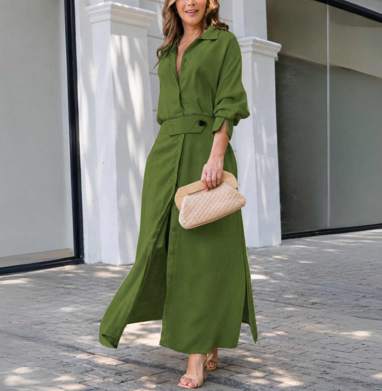 Green - Woman walking outdoors wearing a long textured linen maxi dress with long sleeves, a collar, button front, and waist belt, carrying a woven clutch.