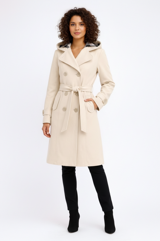 Beige - A woman wearing a cream-coloured, mid-length double-breasted trench coat with a hood, a tied waist belt, and black pants.