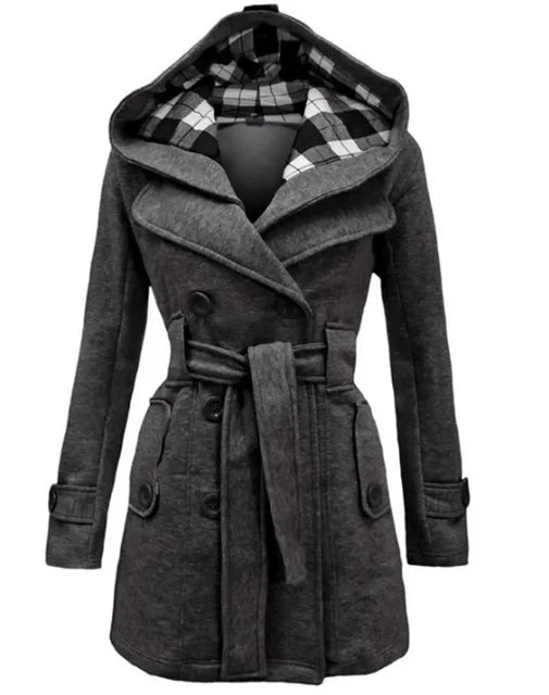 Grey - A woman wearing a cream-coloured, mid-length double-breasted trench coat with a hood, a tied waist belt, and black pants.