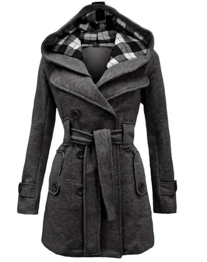 Grey - A woman wearing a cream-coloured, mid-length double-breasted trench coat with a hood, a tied waist belt, and black pants.