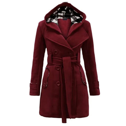 Bordeaux Red - A woman wearing a cream-coloured, mid-length double-breasted trench coat with a hood, a tied waist belt, and black pants.