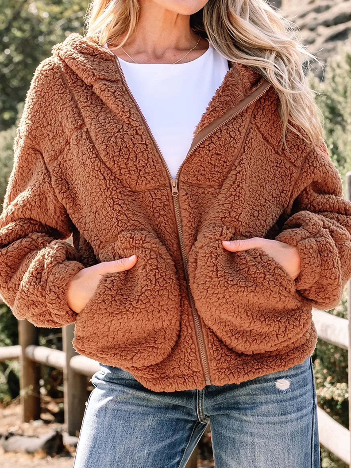Brown - Women's brown hooded teddy fleece jacket with front zipper and patch pockets, worn over a white t-shirt and jeans.