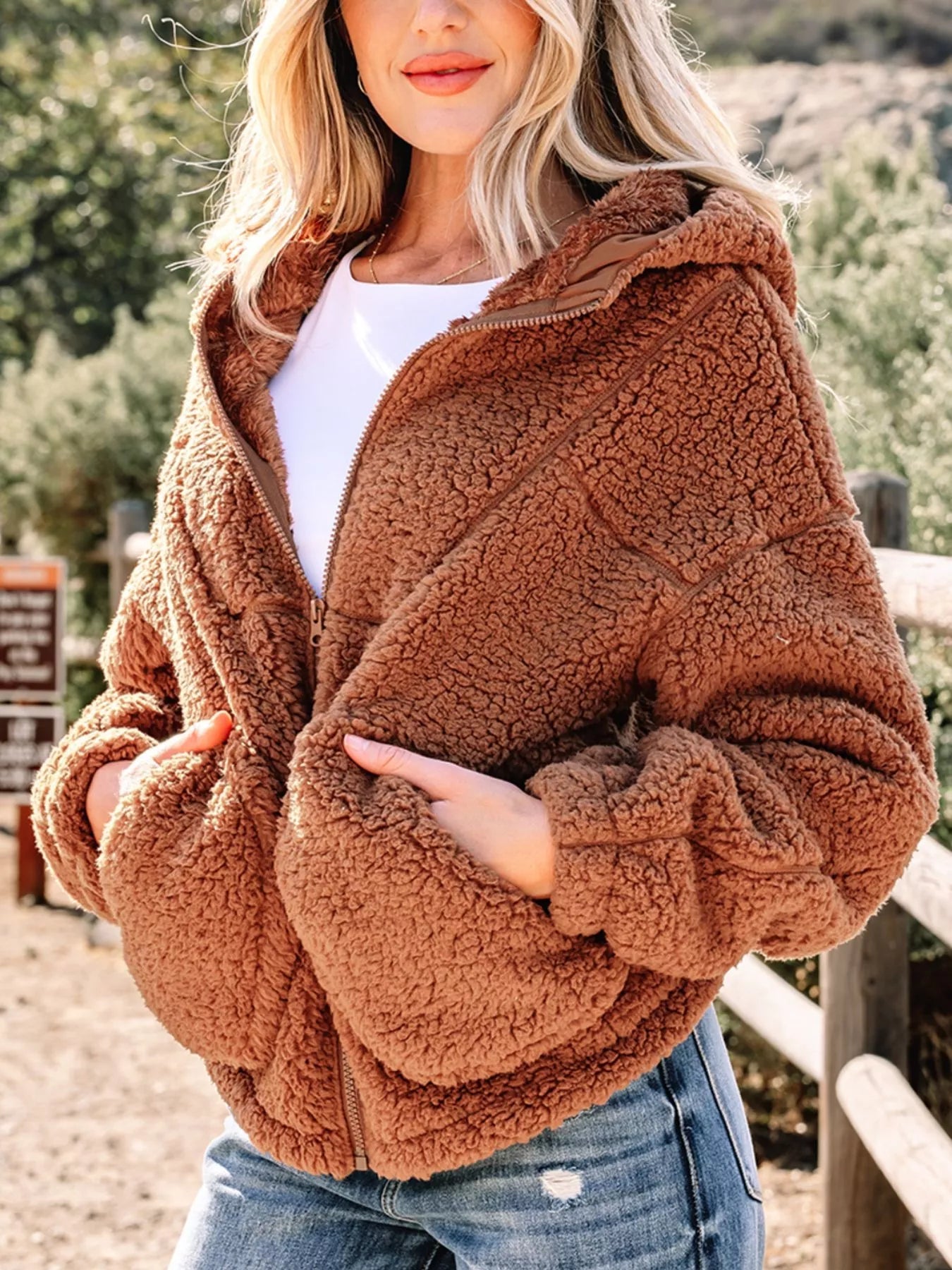 Brown - Women's brown hooded teddy fleece jacket with front zipper and patch pockets, worn over a white t-shirt and jeans.