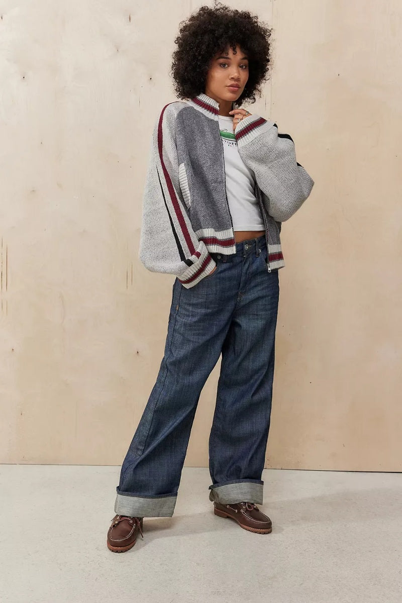Gray - A model wearing a grey colour block knit bomber jacket with a zip front and sporty striped ribbed trims, paired with blue jeans.