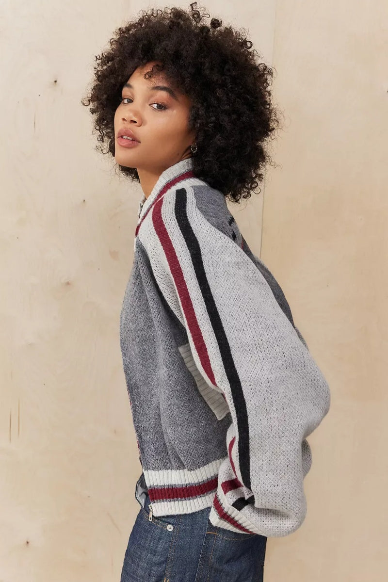 Gray - A model wearing a grey colour block knit bomber jacket with a zip front and sporty striped ribbed trims, paired with blue jeans.