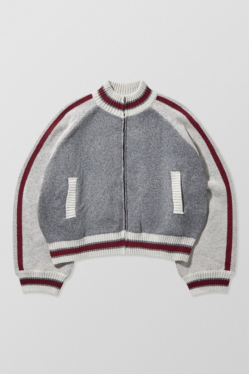 Gray - A model wearing a grey colour block knit bomber jacket with a zip front and sporty striped ribbed trims, paired with blue jeans.