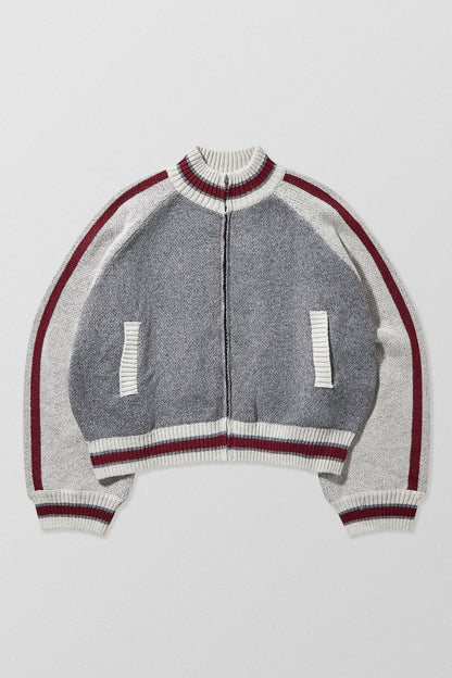Gray - A model wearing a grey colour block knit bomber jacket with a zip front and sporty striped ribbed trims, paired with blue jeans.