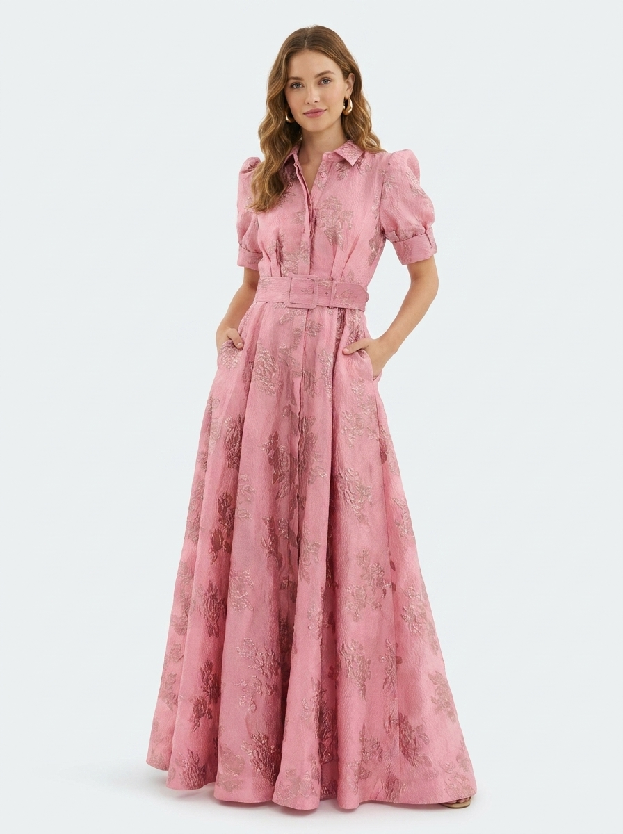 Woman wearing a long heavyweight jacquard maxi dress with a textured floral design, short puff sleeves, collared neckline, button-down front, and matching waist belt