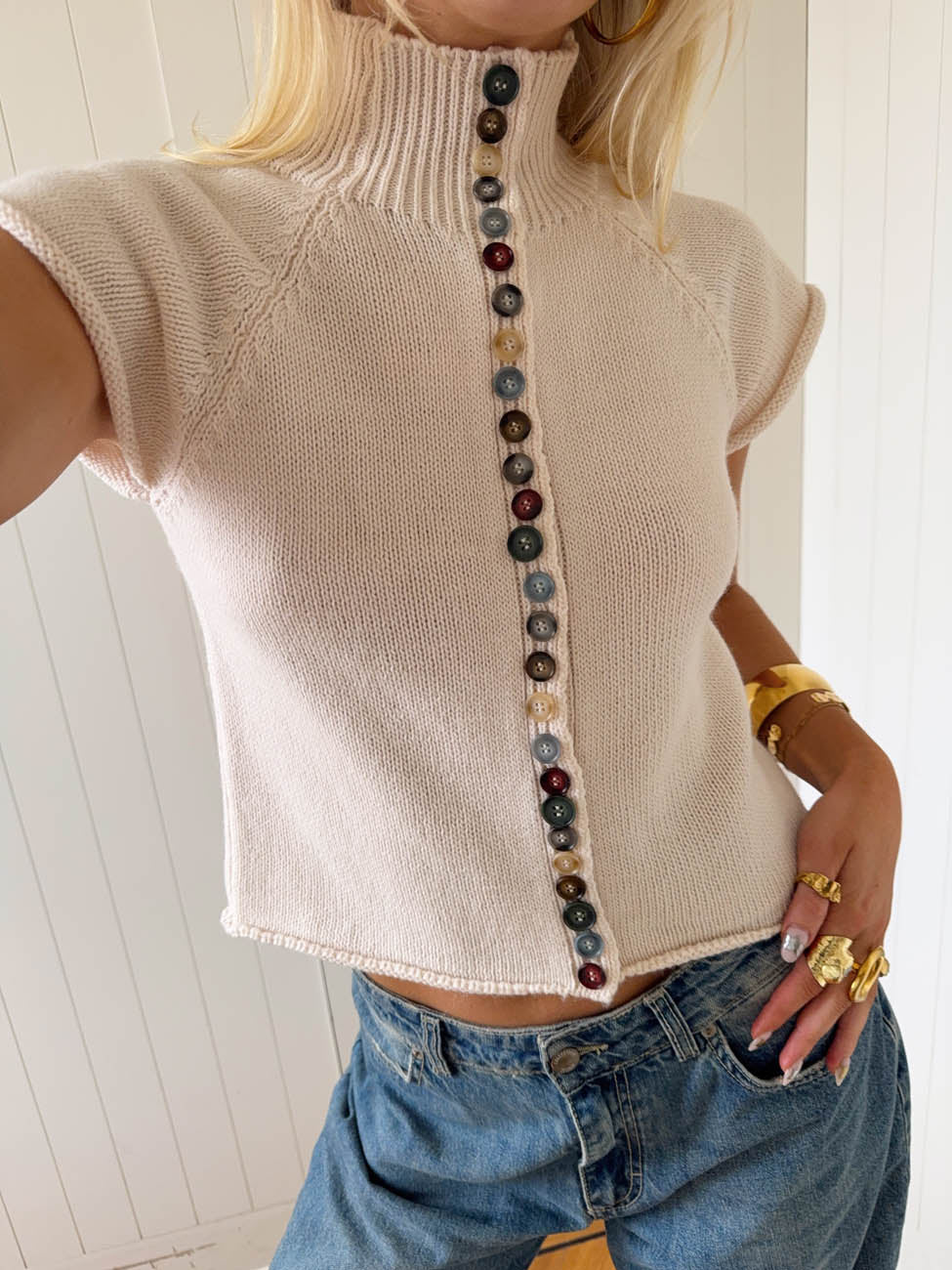 Beige - Women's cream-coloured short-sleeve knit top featuring a ribbed mock neck, rolled raglan sleeves, and a distinctive front closure with a long row of multi-coloured buttons.