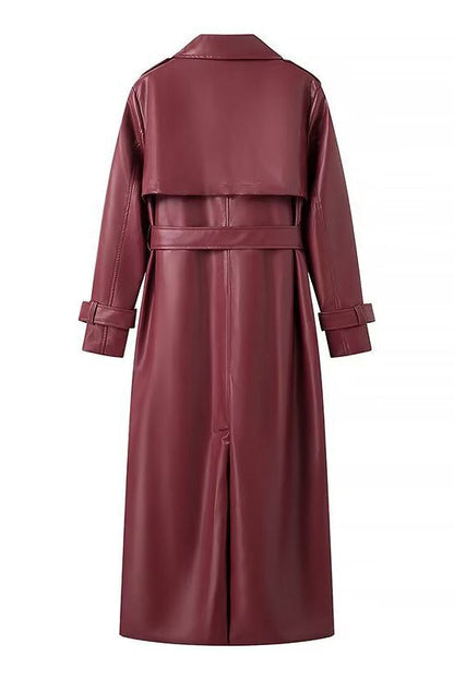Red - A woman walking down a city street wearing a deep burgundy maxi-length trench coat in a smooth leather-look material, styled with a black turtleneck, black stirrup pants, and black heels.