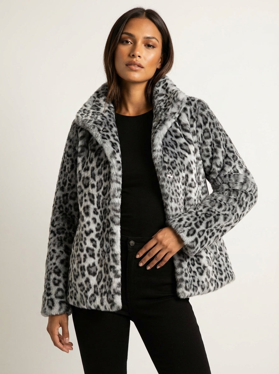 Grey - A woman wearing a cropped leopard print faux fur jacket with a structured collar, styled over a black turtleneck and black leather pants.
