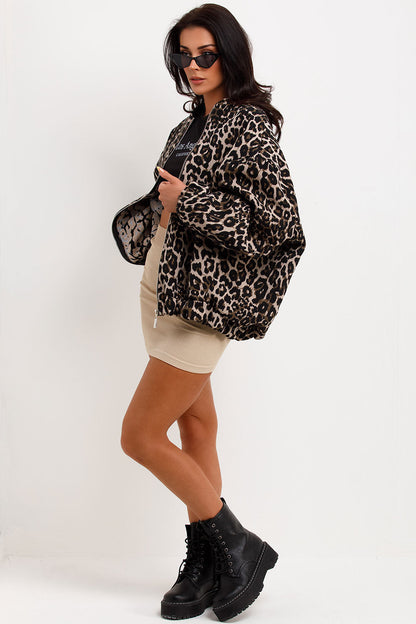 Leopard Print - A woman wearing an oversized bomber jacket with a leopard print, styled over a black crop top and beige ribbed mini skirt.