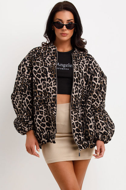 Leopard Print - A woman wearing an oversized bomber jacket with a leopard print, styled over a black crop top and beige ribbed mini skirt.