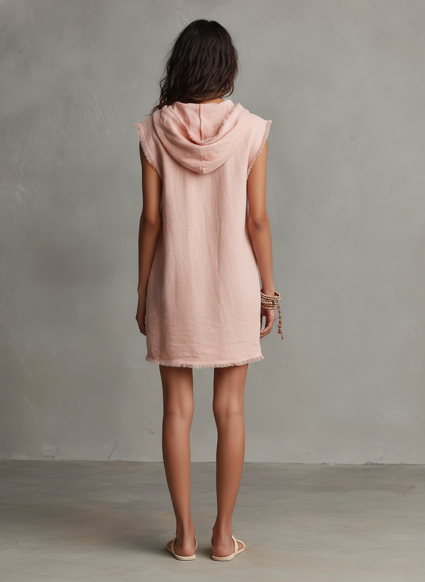 Pink - A front view of a model wearing a sleeveless, pale pink textured linen mini dress featuring a hood with drawstrings, frayed edges, front patch pockets, and a relaxed shift silhouette.