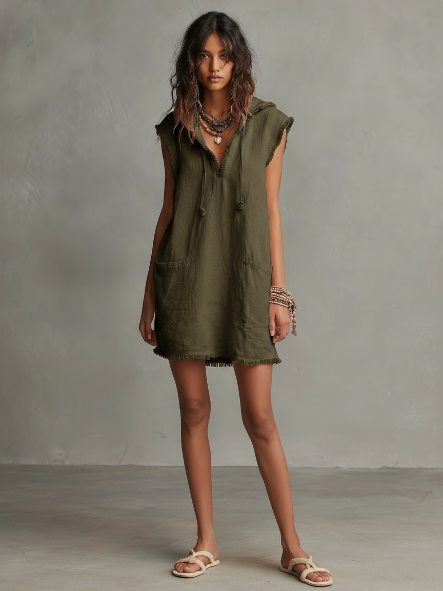 Photo Color - A front view of a model wearing a sleeveless, pale pink textured linen mini dress featuring a hood with drawstrings, frayed edges, front patch pockets, and a relaxed shift silhouette.