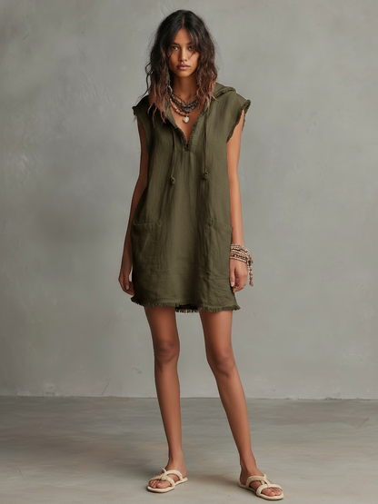 Photo Color - A front view of a model wearing a sleeveless, pale pink textured linen mini dress featuring a hood with drawstrings, frayed edges, front patch pockets, and a relaxed shift silhouette.