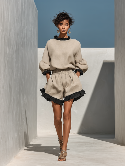 Beige - A model wearing an oatmeal-coloured linen two-piece set featuring a high-neck long-sleeve top and matching shorts, both detailed with contrast black ruffle trims along the collar, cuffs, and hems.