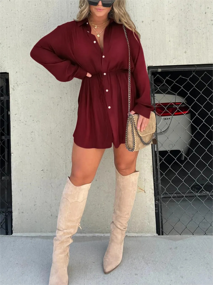 Burgundy - Woman wearing a long sleeve button front shirt dress with an adjustable tie waist.