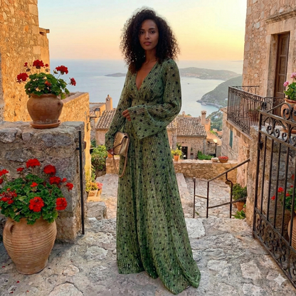 2XL - A woman wearing a long-sleeved, plunging V-neck maxi dress in olive green chiffon with gold metallic vertical stripes and dark abstract spots, holding a gold quilted clutch bag.