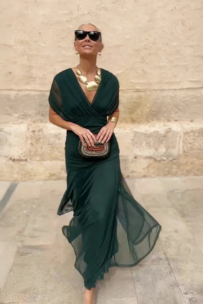 Bottle- green - A woman walking outdoors wearing an elegant off-the-shoulder midi dress featuring a ruched bodice and a vibrant abstract floral print in shades of green, purple, and pink.