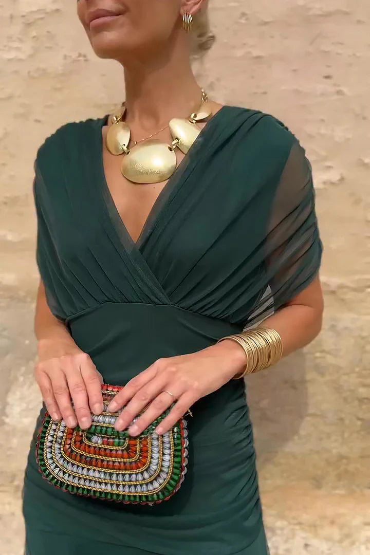 Bottle- green - A woman walking outdoors wearing an elegant off-the-shoulder midi dress featuring a ruched bodice and a vibrant abstract floral print in shades of green, purple, and pink.