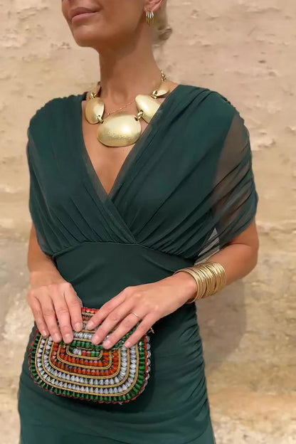 Bottle- green - A woman walking outdoors wearing an elegant off-the-shoulder midi dress featuring a ruched bodice and a vibrant abstract floral print in shades of green, purple, and pink.