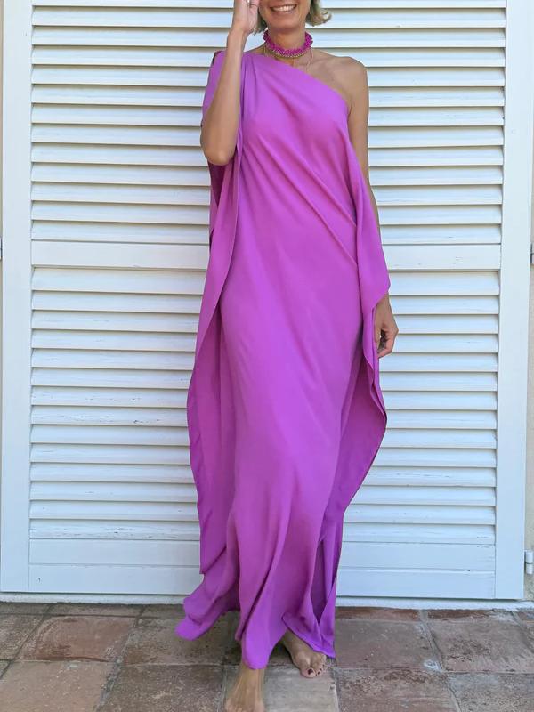Cyclamen - A woman wearing a black one-shoulder asymmetric chiffon maxi dress with a flowing cape sleeve, styled with gold cuff bracelets and sunglasses against a white shuttered background.