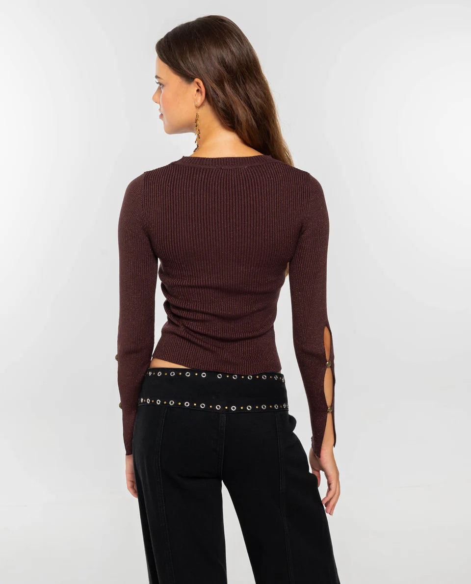 Women's dark burgundy ribbed knit long-sleeve top featuring cut-out details across the chest and forearms, held together by round metallic hardware.
