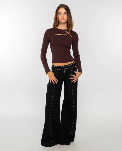 Women's dark burgundy ribbed knit long-sleeve top featuring cut-out details across the chest and forearms, held together by round metallic hardware.