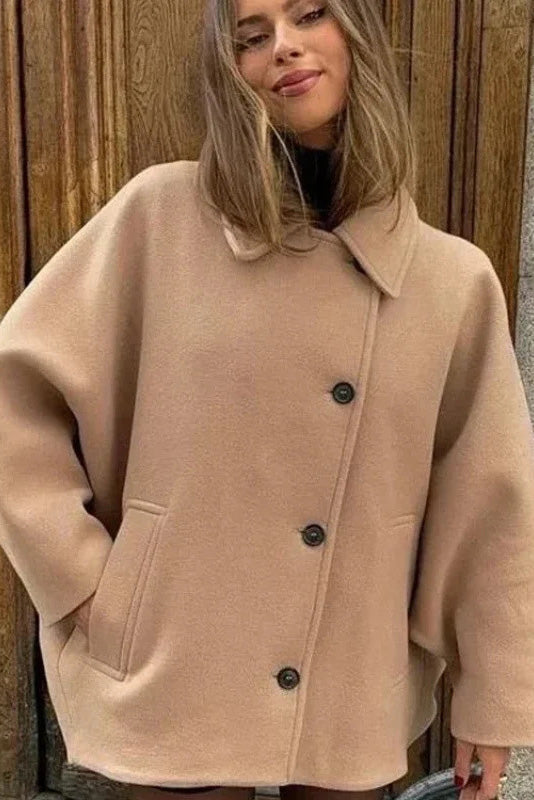 Khaki - A woman wearing a black oversized felted jacket with wide sleeves and notch lapels, styled with a grey turtleneck and black shorts.