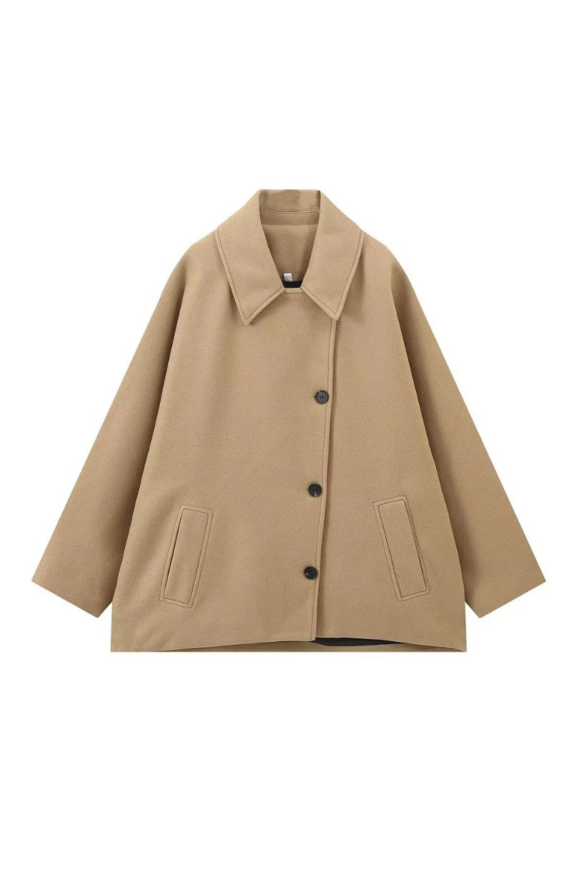Khaki - A woman wearing a black oversized felted jacket with wide sleeves and notch lapels, styled with a grey turtleneck and black shorts.