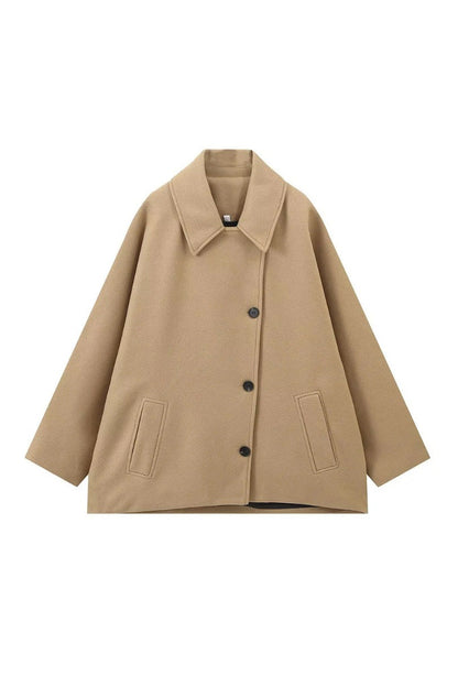 Khaki - A woman wearing a black oversized felted jacket with wide sleeves and notch lapels, styled with a grey turtleneck and black shorts.