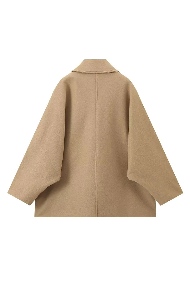 Khaki - A woman wearing a black oversized felted jacket with wide sleeves and notch lapels, styled with a grey turtleneck and black shorts.