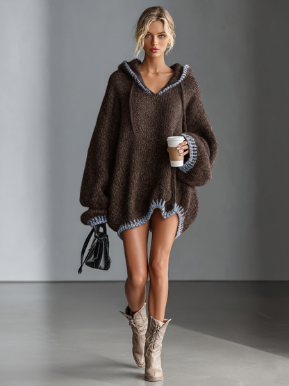 Dark Brown - A woman wearing an oversized charcoal grey textured knit hooded jumper with contrast pink whipstitch detailing on the hood, cuffs, and hem, styled with beige lace-up boots.