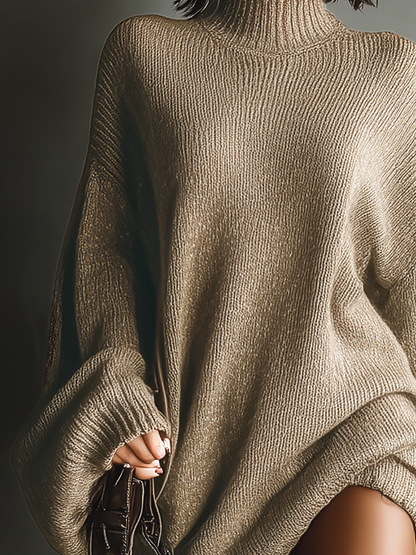 Gray - A person wearing an oversized, taupe-brown ribbed knit high-neck jumper with slouchy balloon sleeves, styled with matching over-the-knee boots.