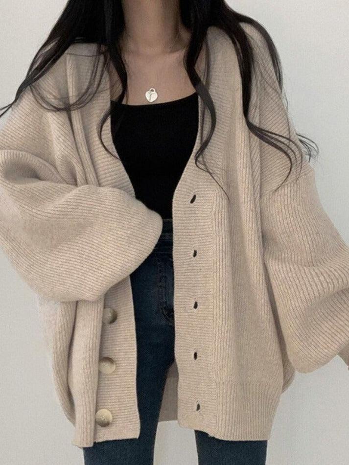 Beige - Women's oversized ribbed knit cardigan featuring a V-neckline, large button closures, and voluminous balloon sleeves with fitted cuffs, styled open over a black top.