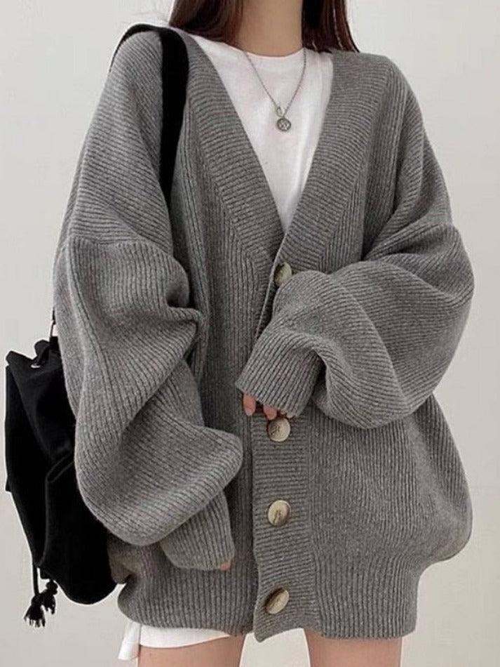 Gray - Women's oversized ribbed knit cardigan featuring a V-neckline, large button closures, and voluminous balloon sleeves with fitted cuffs, styled open over a black top.