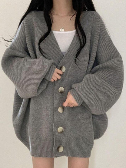Gray - Women's oversized ribbed knit cardigan featuring a V-neckline, large button closures, and voluminous balloon sleeves with fitted cuffs, styled open over a black top.