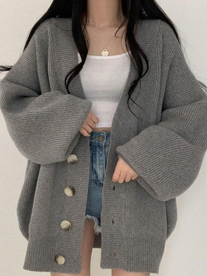 Gray - Women's oversized ribbed knit cardigan featuring a V-neckline, large button closures, and voluminous balloon sleeves with fitted cuffs, styled open over a black top.