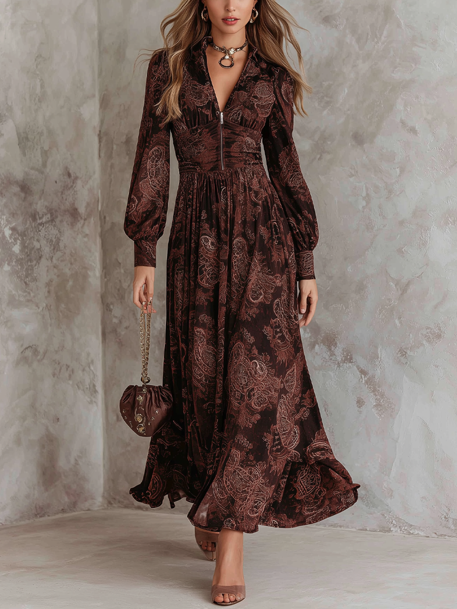 2XL - A woman wearing a long-sleeved, brown paisley print maxi dress with a zippered V-neckline, ruched bodice, and flowing skirt, holding a small brown satin handbag.