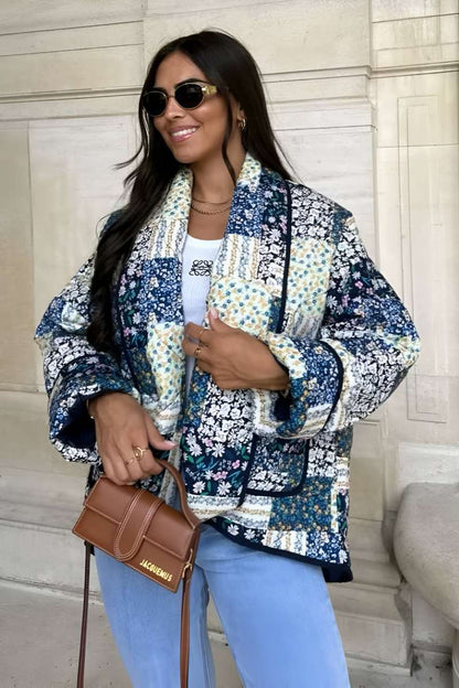 Woman wearing a quilted longline jacket featuring a blue and white floral patchwork design with contrasting dark binding.