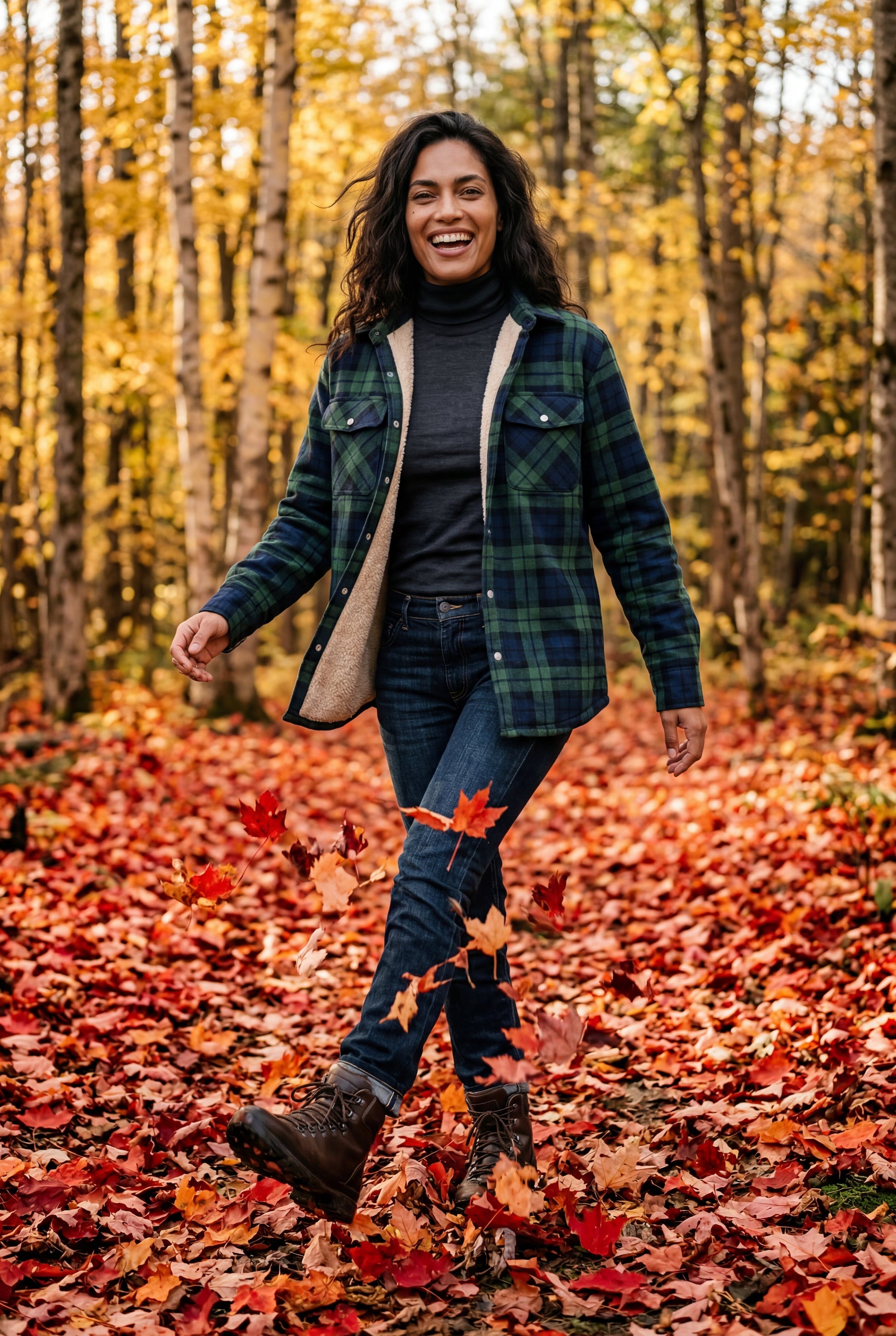 Green - A woman wearing a brown plaid check shirt jacket with a cream-coloured sherpa lining, styled with dark blue slim-fit jeans and brown leather lace-up boots against a plain grey background.