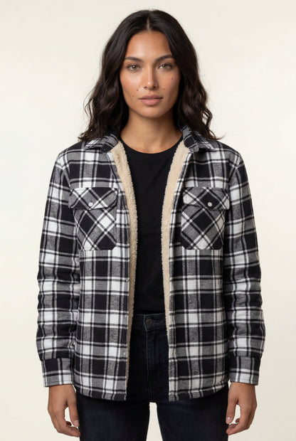 Black - A woman wearing a brown plaid check shirt jacket with a cream-coloured sherpa lining, styled with dark blue slim-fit jeans and brown leather lace-up boots against a plain grey background.