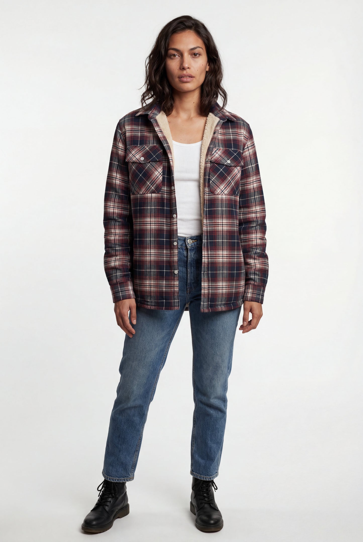 Red - A woman wearing a brown plaid check shirt jacket with a cream-coloured sherpa lining, styled with dark blue slim-fit jeans and brown leather lace-up boots against a plain grey background.