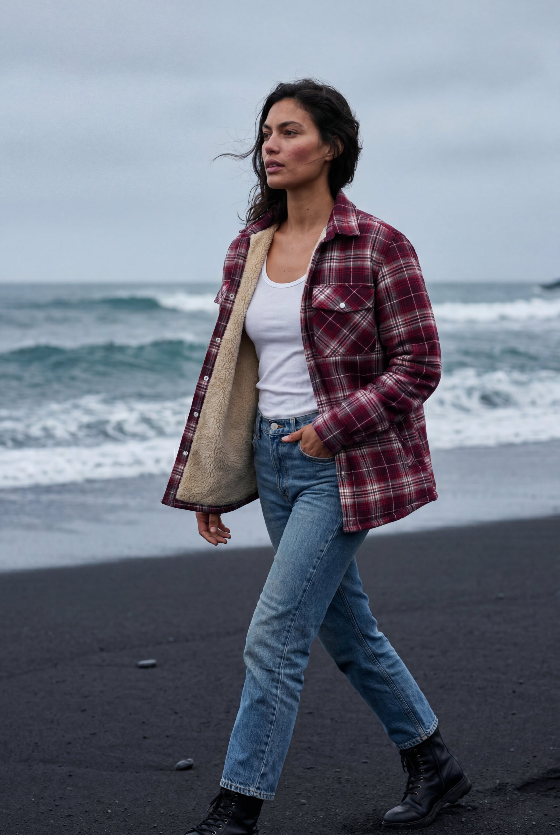 Red - A woman wearing a brown plaid check shirt jacket with a cream-coloured sherpa lining, styled with dark blue slim-fit jeans and brown leather lace-up boots against a plain grey background.
