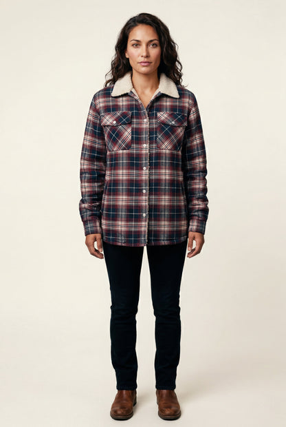 Navy Blue - A woman wearing a brown plaid check shirt jacket with a cream-coloured sherpa lining, styled with dark blue slim-fit jeans and brown leather lace-up boots against a plain grey background.