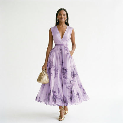 Purple - A woman wearing a pale green long-sleeve maxi dress with a dark green floral motif, featuring a pleated chiffon texture, V-neckline, and a flowing skirt.