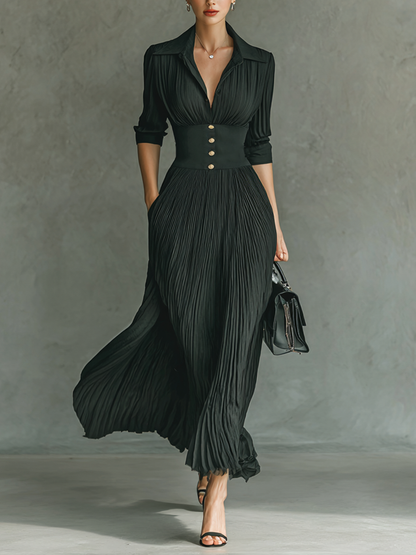 Black - A woman wearing a sophisticated black pleated maxi dress with a structured corset waistband, gold buttons, a spread collar, and elbow-length sleeves.