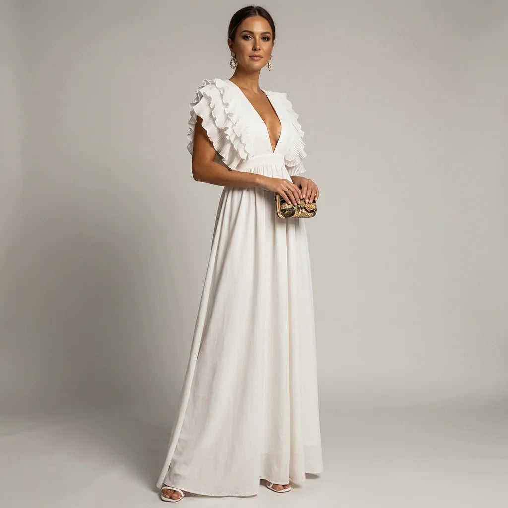 White - A woman wearing a floor-length cornflower blue maxi dress with a plunging V-neckline and voluminous, finely pleated ruffle sleeves, holding a gold clutch.